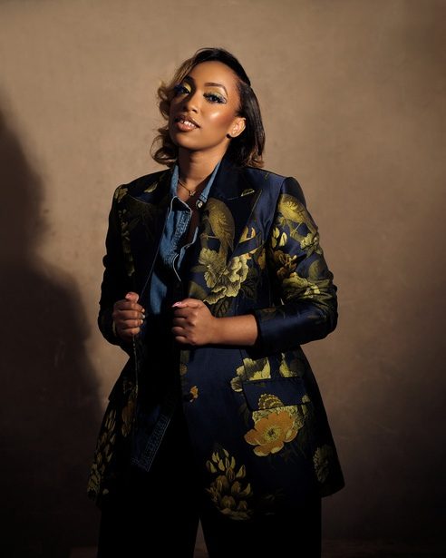 Eki Ogunbor in a navy and gold brocade blazer