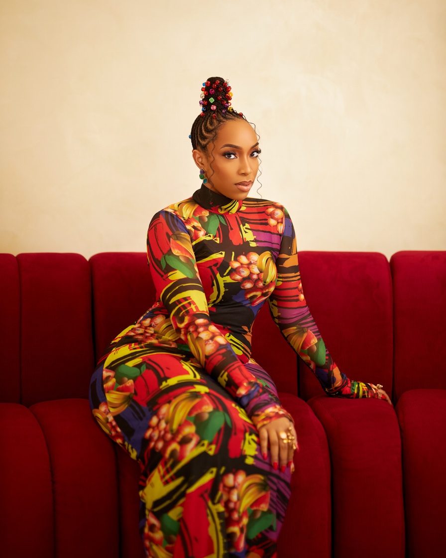 Eki Ogunbor in a bold printed catsuit on a red velvet sofa
